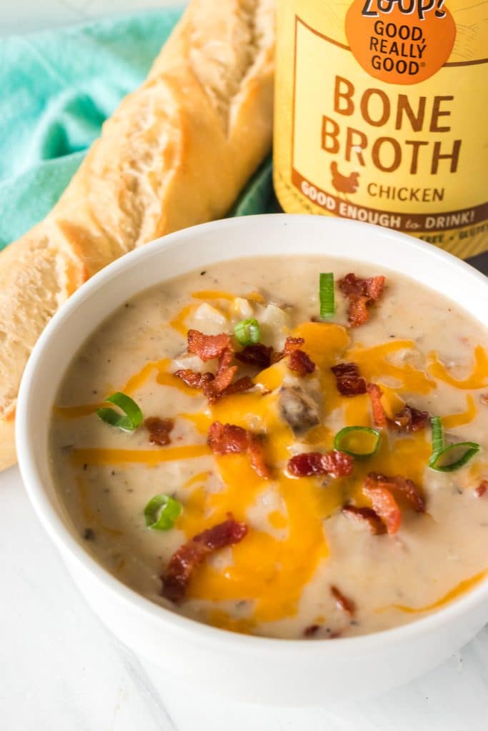 bowl of loaded potato soup next to a jar of zoup bone broth.