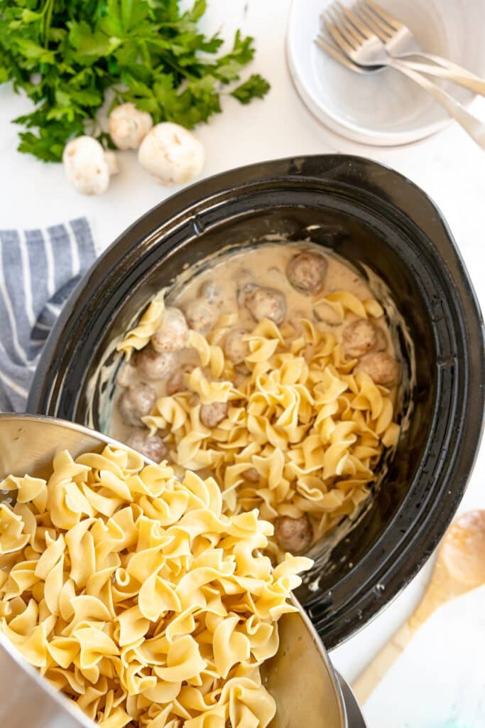 egg noodles pouring into a crockpot.