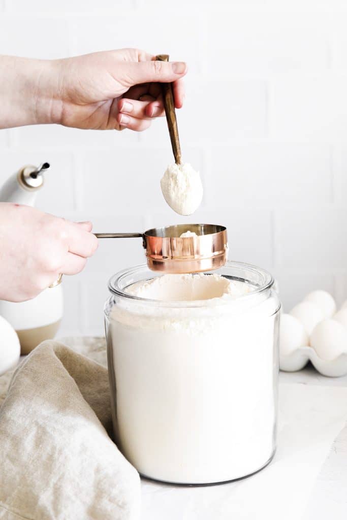 spoon adding flour to a measuring cup.