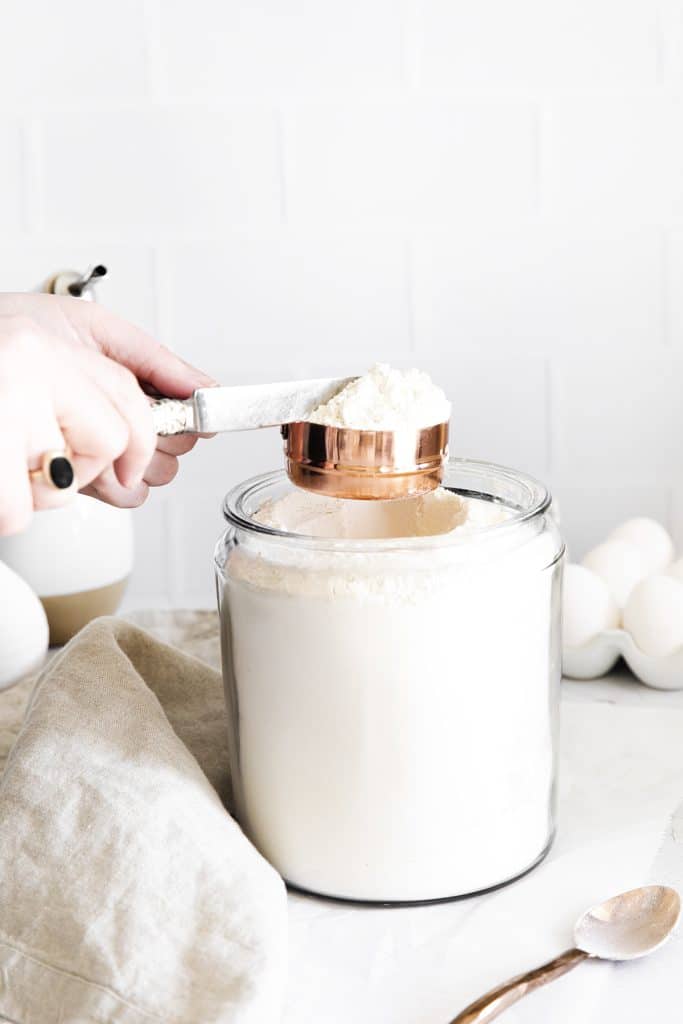 knife scraping excess flour off a measuring cup.
