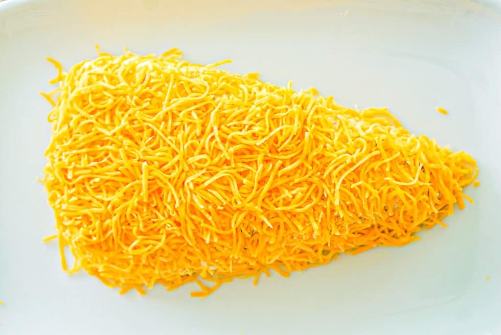 overhead shot of a cheese covered cheese ball shaped like a carrot.