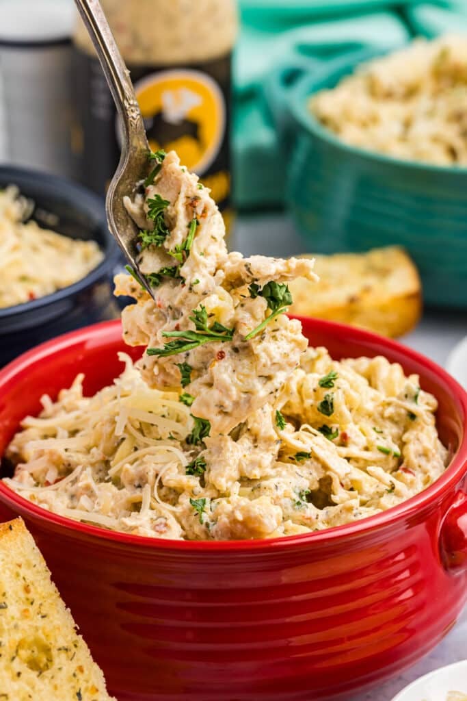 fork getting a bite of parmesan chicken pasta from a bowl.