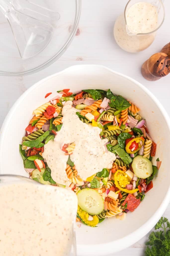 dressing pouring onto a pasta salad.