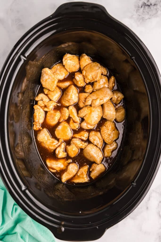 chicken and sauce in a black crockpot.