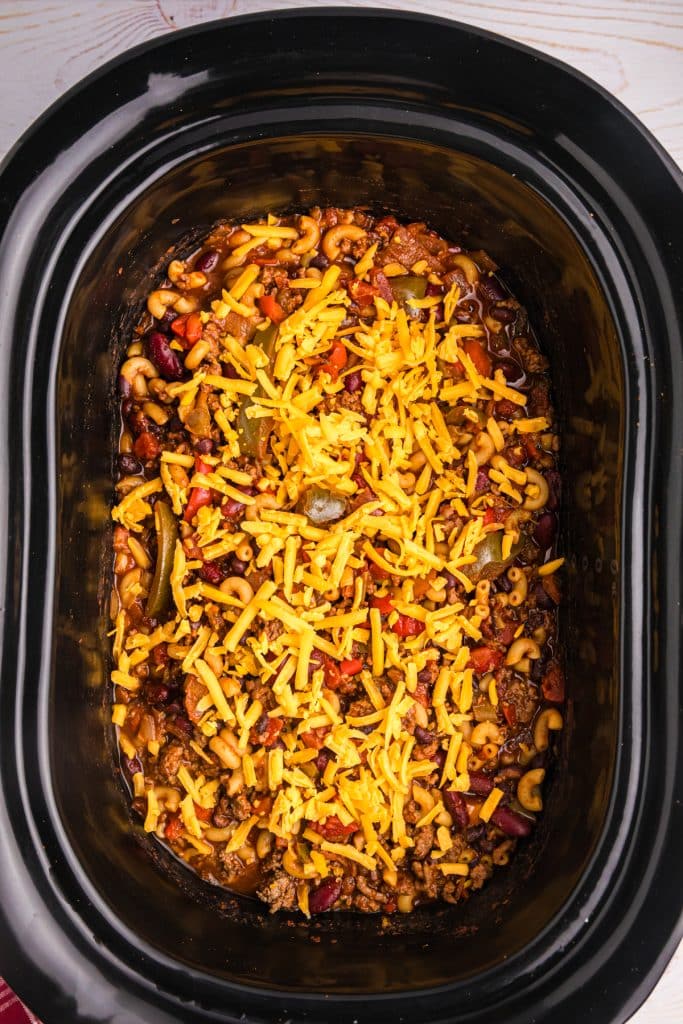 shredded cheddar sprinkled on chili in a slow cooker.