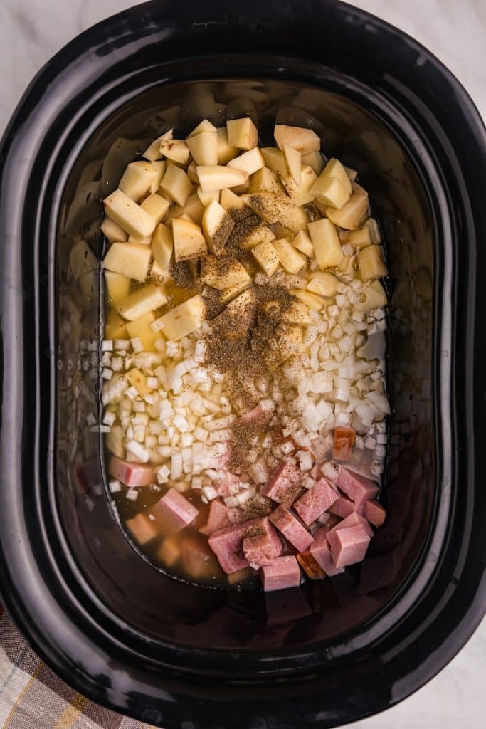 overhead shot of potatoes & ham in a black crockpot.