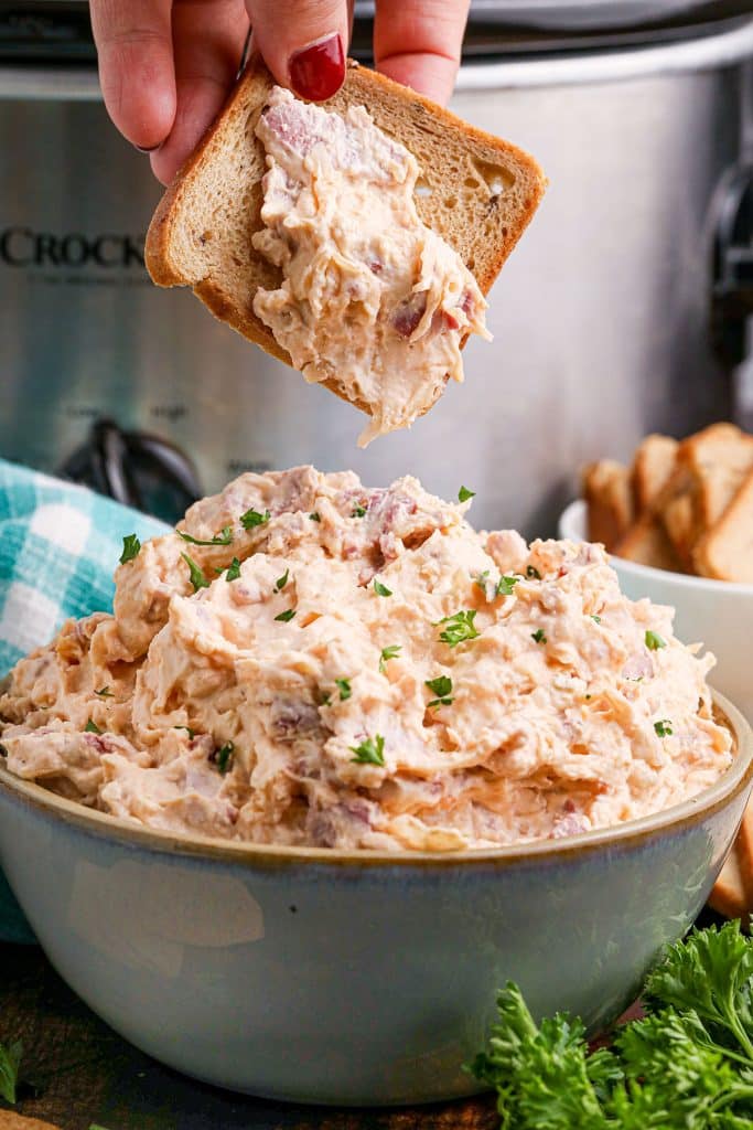 rye bread square dipping into a bowl of reuben dip.