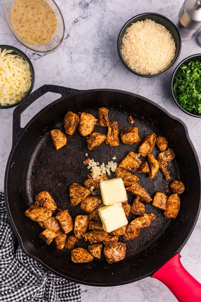 overhead shot of chicken and butter in a skillet.