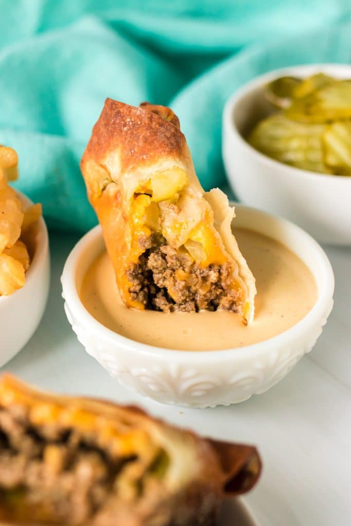 big mac egg roll dipped into a bowl of special sauce.