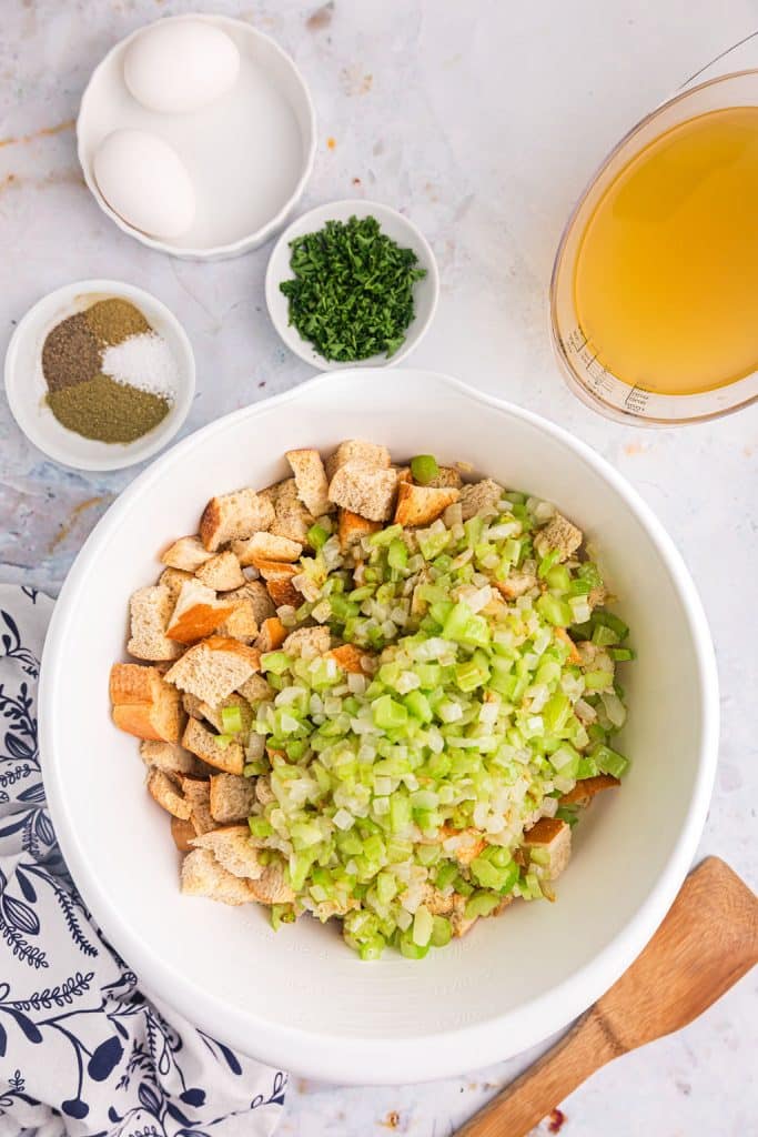 overhead shot of bread cubes, oniones, and celery in a mixing bowl.