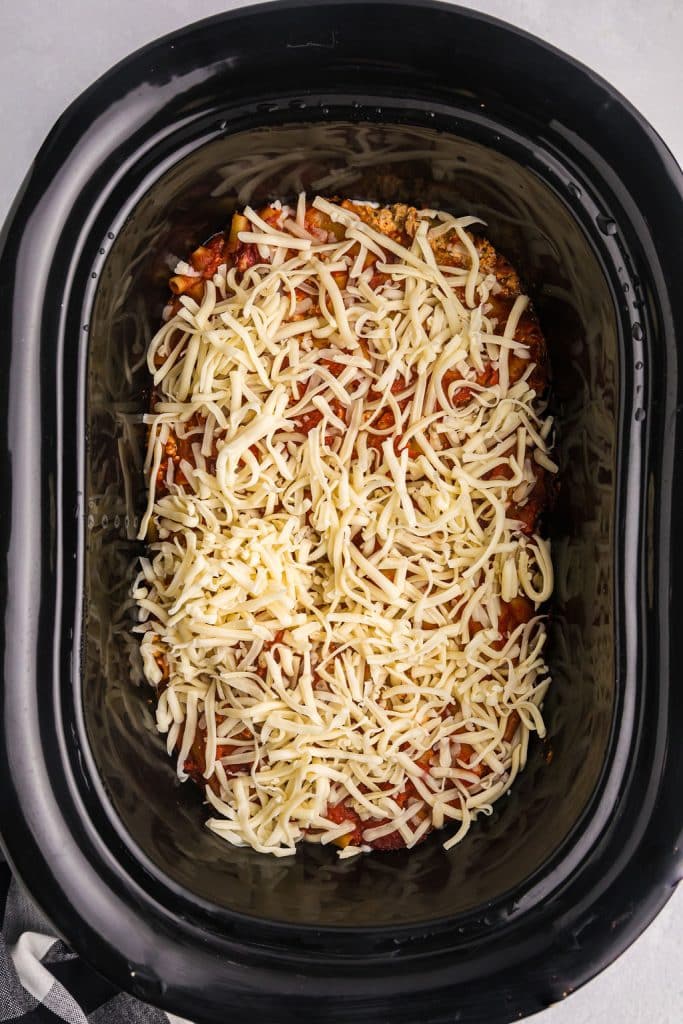 mozzarella cheese sprinkled in a black slow cooker.