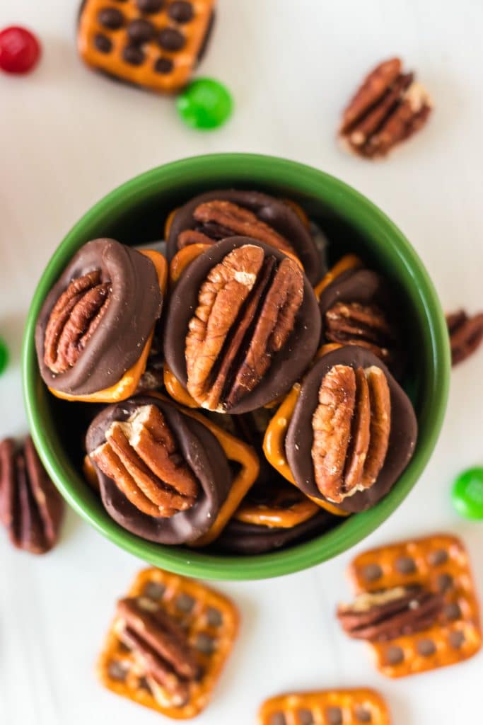 overhead shot of a bowl of rolo pretzels with pecan halves.