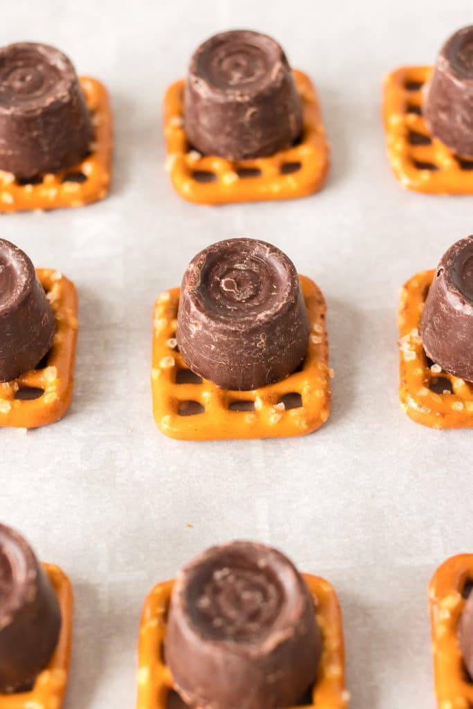 a rolo chocolate sitting on top of a rectangle pretzel.