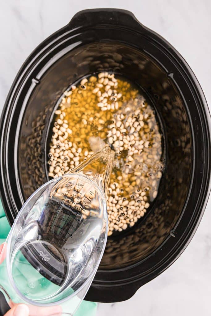 water pouring into a pot of peas.