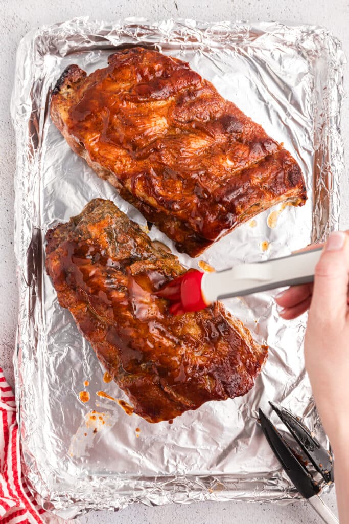 brush basting ribs with sauce.