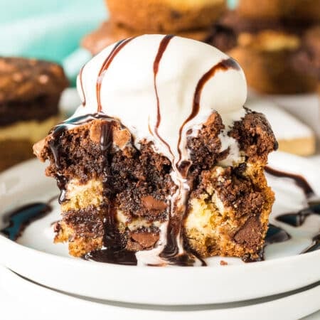 a brookie cheesecake cup topped with vanilla ice cream and hot fudge dripping down.