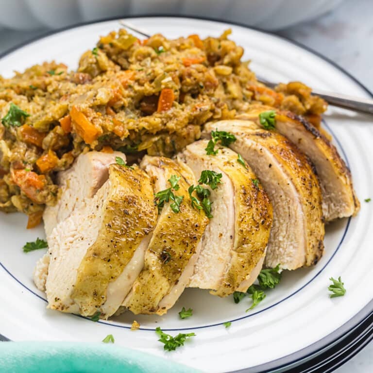 sliced chicken breast with stuffing on a white plate.