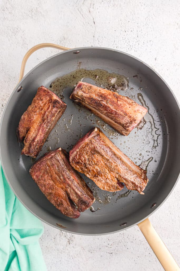 short ribs being seared in a skillet.