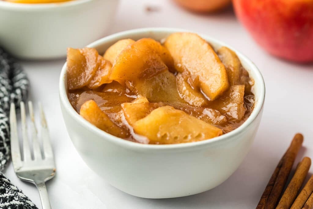 bowl of fried apples next to a fork.