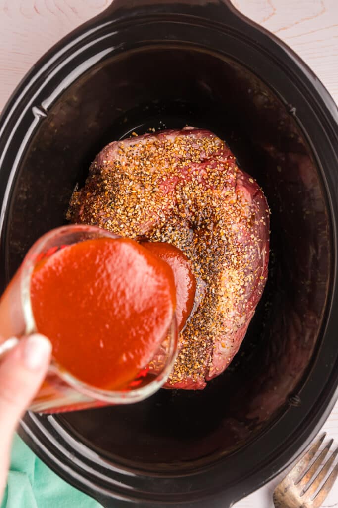 arby's sauce pouring into a crockpot.