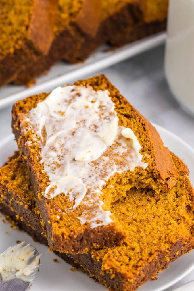 slice of buttered pumpkin bread with a bite missing.