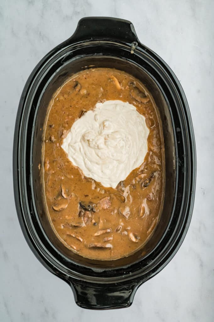 sour cream gravy mixing into a crockpot.