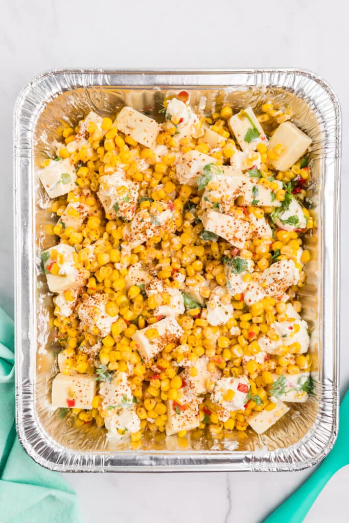 corn and cheeses in an aluminum pan to make corn dip.