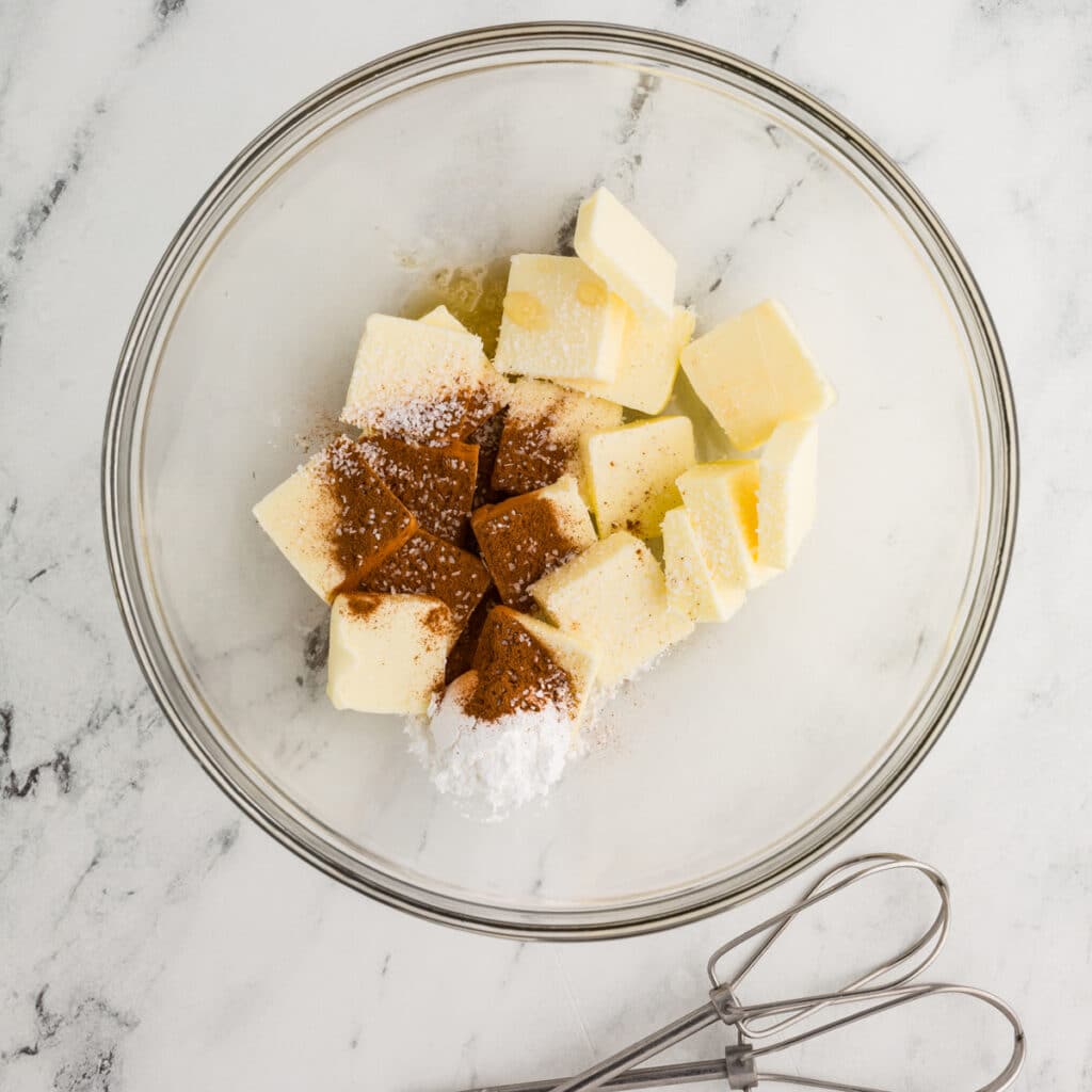 overhead shot of butter, cinnamon, and powdered sugar in a mixing bowl.