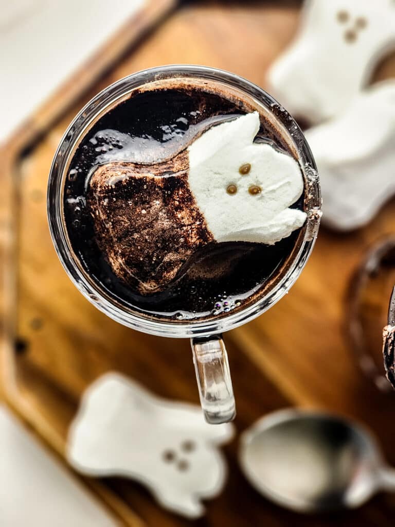ghost peep marshmallow floating in a mug of black hot cocoa.