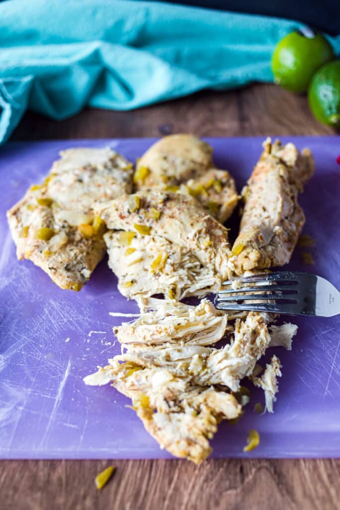 shredded chicken on a purple cutting board with a fork.