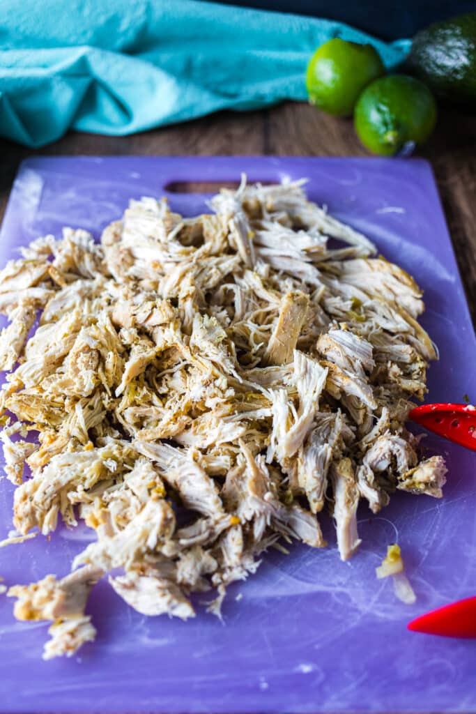 shredded chicken on a purple cutting board.