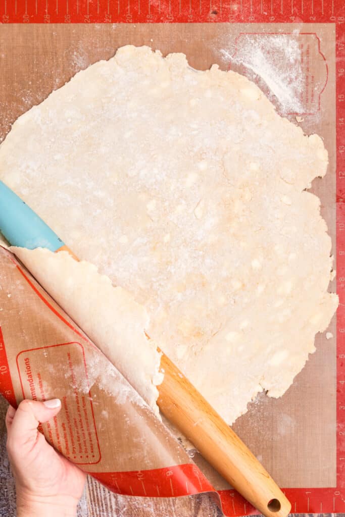 rolling pin rolling out pie crust on a silicone mat.