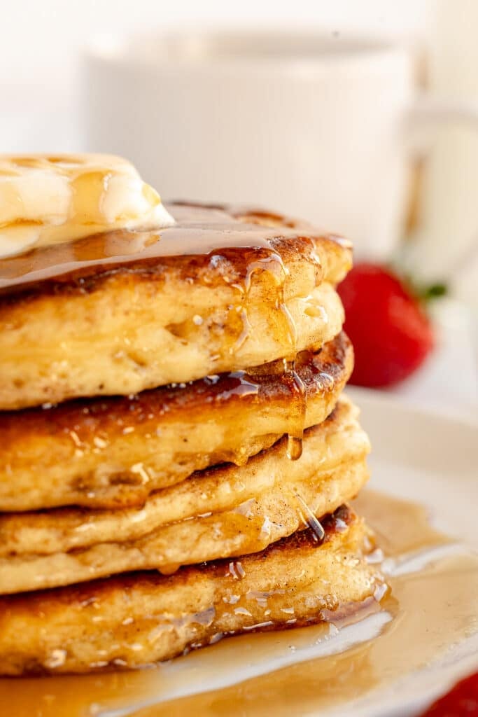 side view of a stack of pancakes dripping with syrup.