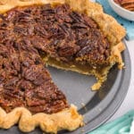 side view of a pecan pie with a slice missing.