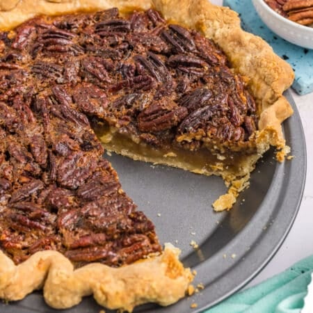 side view of a pecan pie with a slice missing.