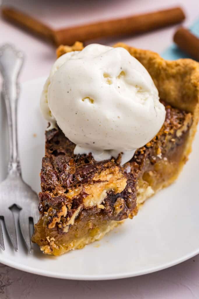 slice of pecan pie topped with a scoop of vanilla ice cream.