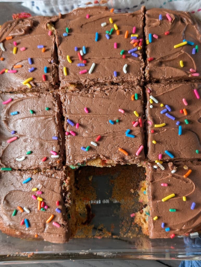 overhead shot a chocolate frosted cake with rainbow sprinkles.