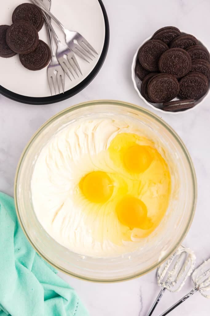 Cream cheese and eggs in a mixing bowl.