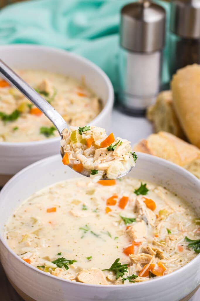 spoon lifting a bite of creamy turkey rice soup from a bowl.
