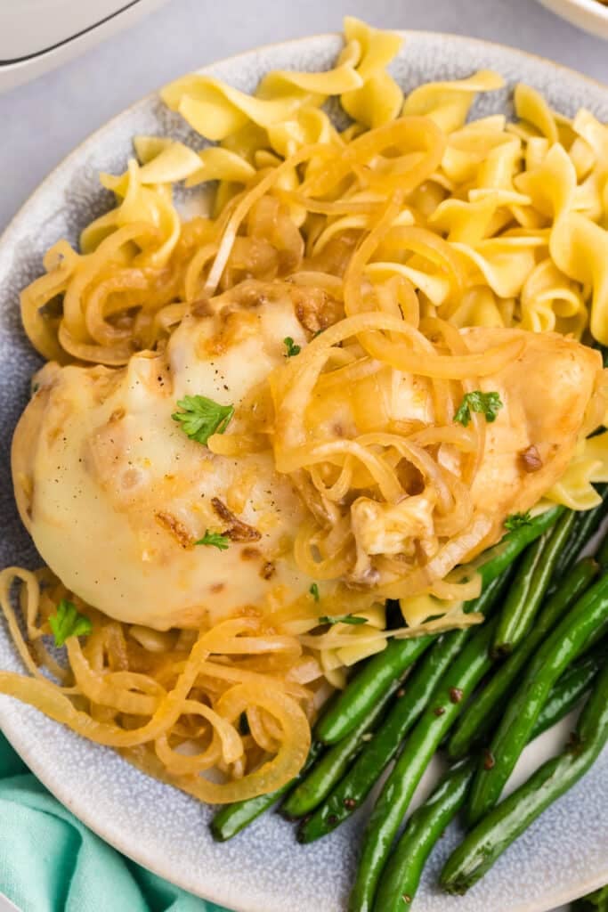 overhead shot of french onion chicken on a plate with green beans.