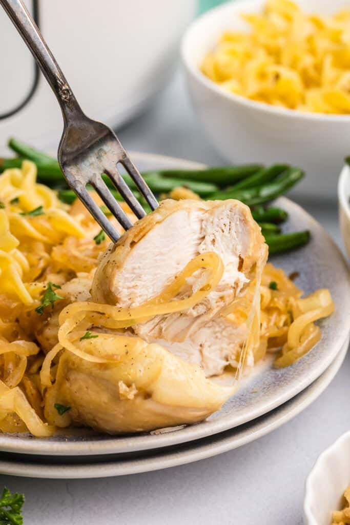 fork lifting a bite of chicken breast from a plate.