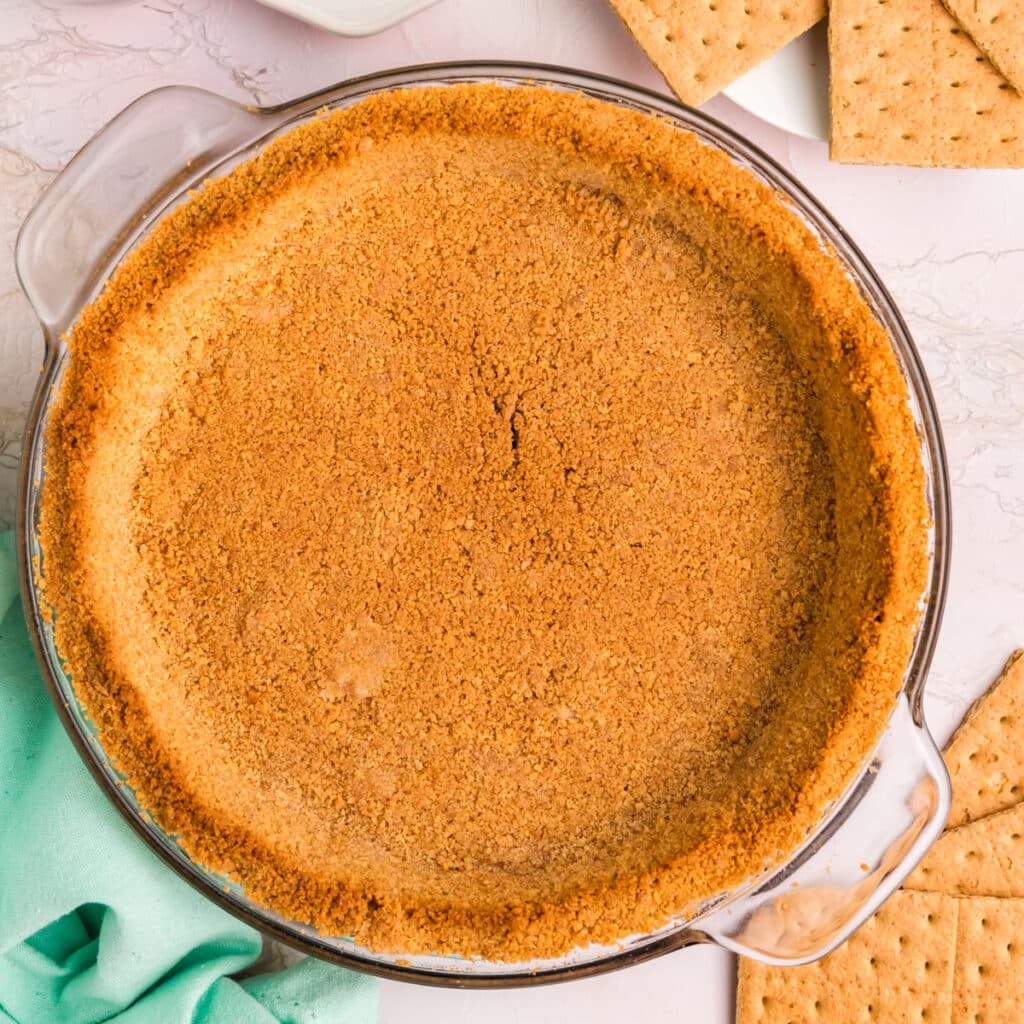 Golden graham cracker crust in a glass pie dish.