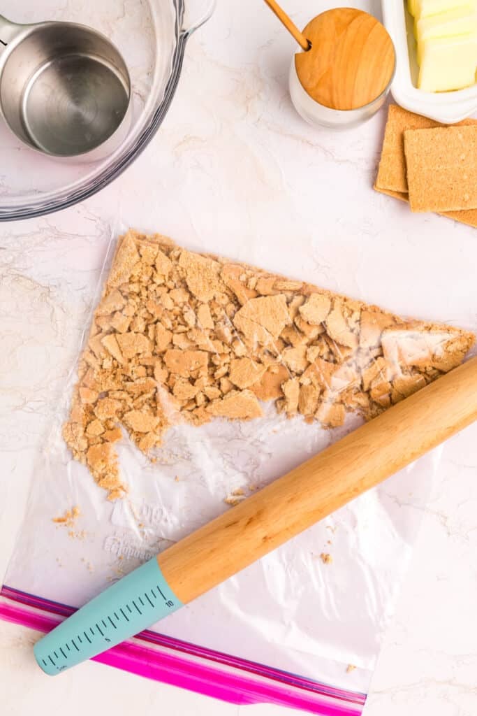 Crushing graham crackers with a rolling pin.