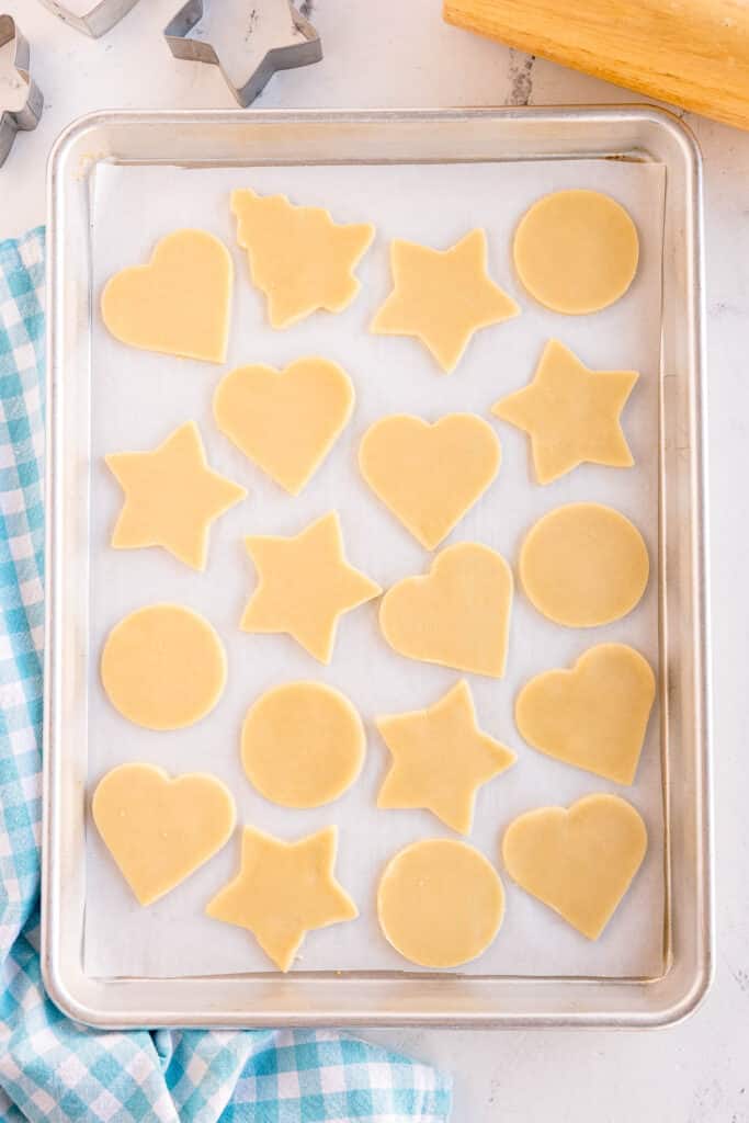 Unbaked cut-out cookies arranged on a baking sheet.