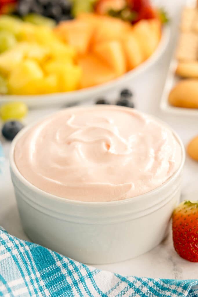 bowl of creamy fruit dip surrounded by fruit.