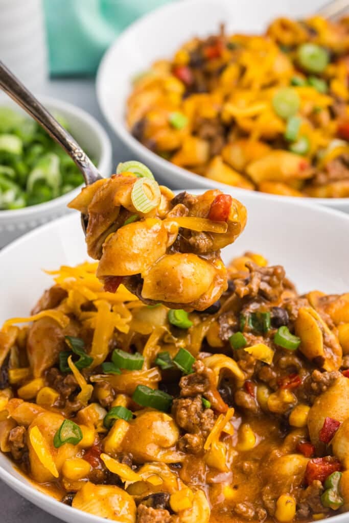 spoon lifting a bite of taco pasta from a bowl.