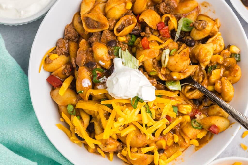 overhead shot of a bowl of taco pasta topped with sour cream and cheese.
