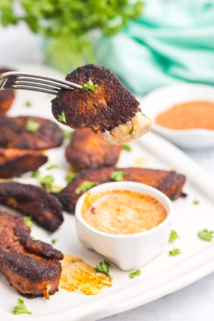 fork with a bite of blackened chicken on it.