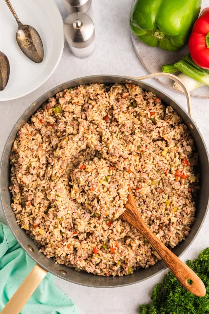 skillet of dirty rice with a wooden spoon in it.