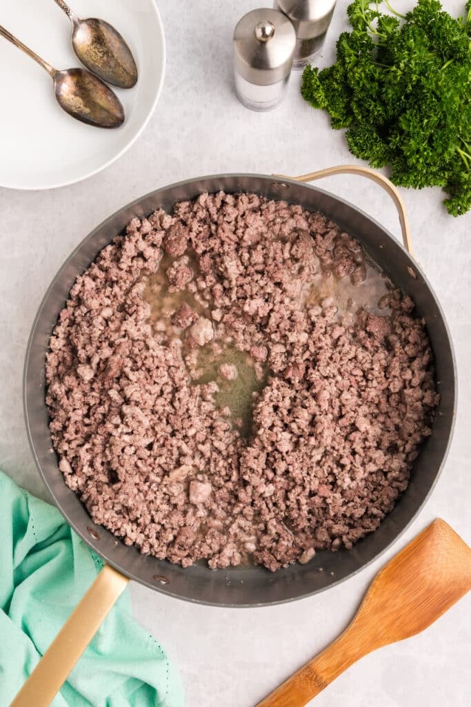 Ground meat cooking in a large skillet.